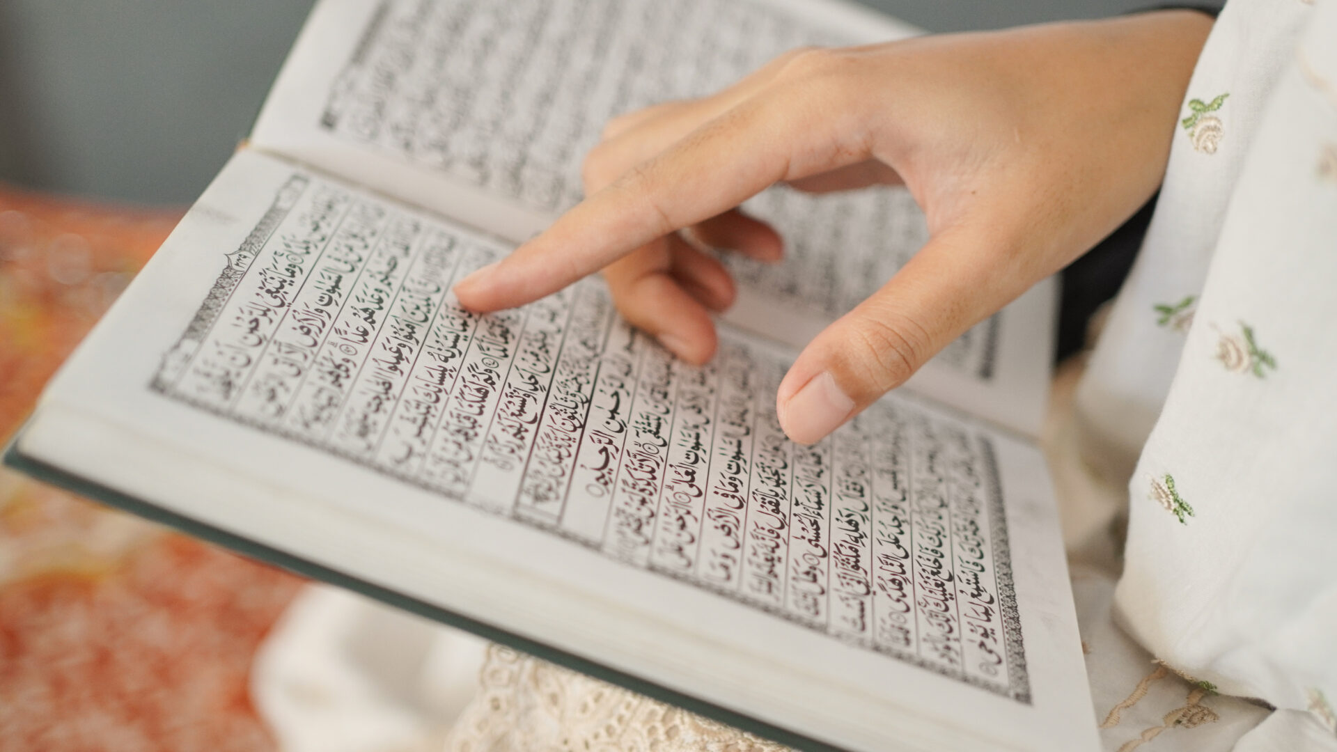 Main d'une femme pointé sur le Coran